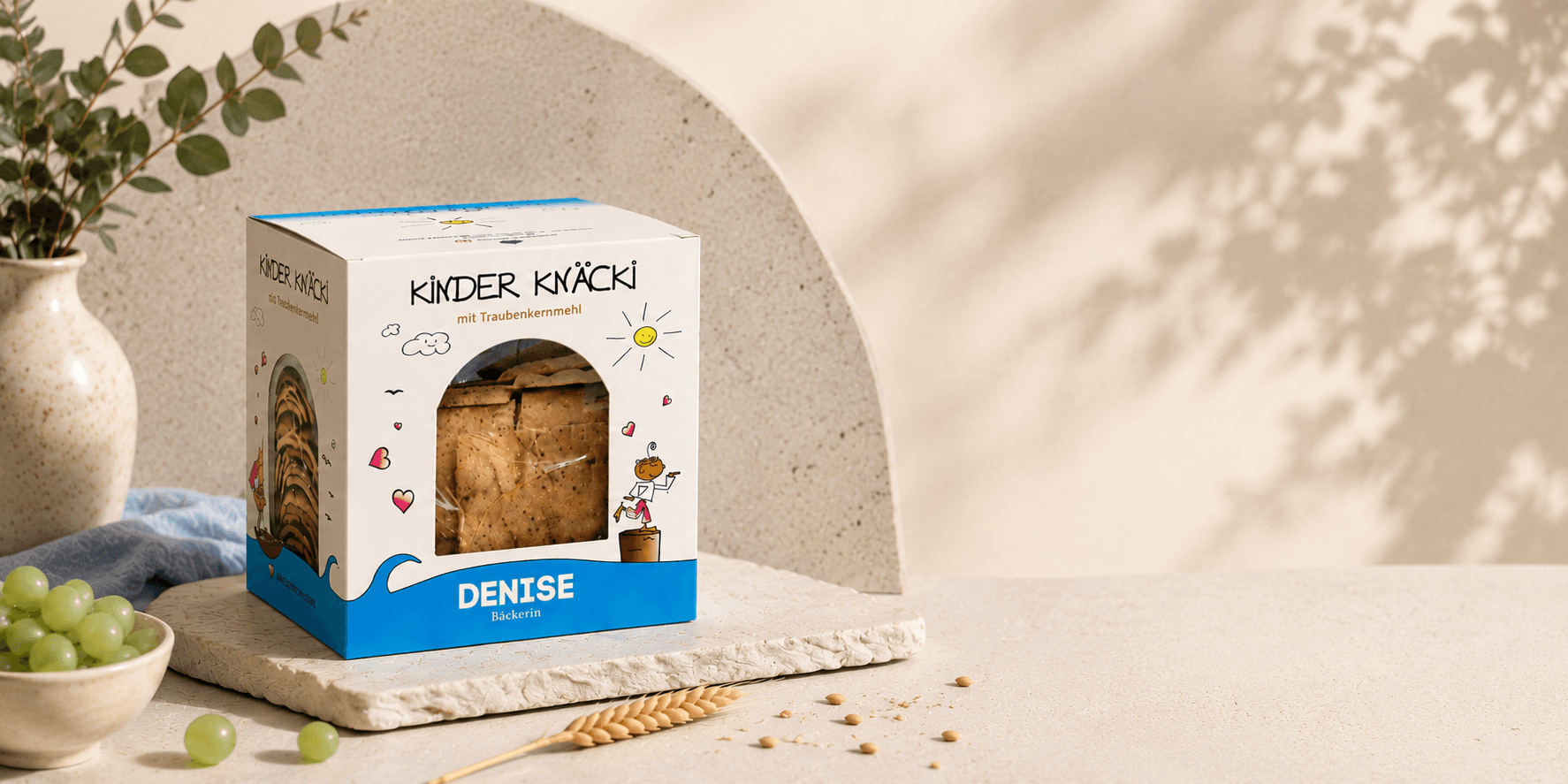 Kinder Knäcki Packung auf hellem Tisch mit Trauben und Getreide