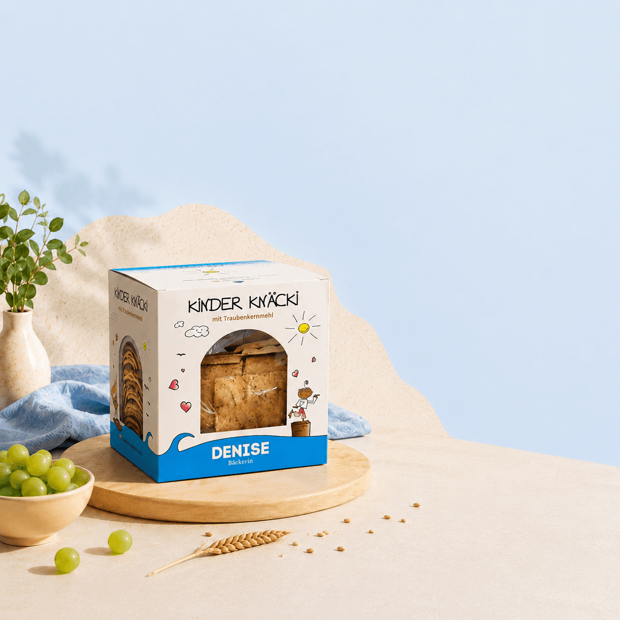 Kinder Knäcki Packung mit Trauben und Getreide auf hellblauem Hintergrund